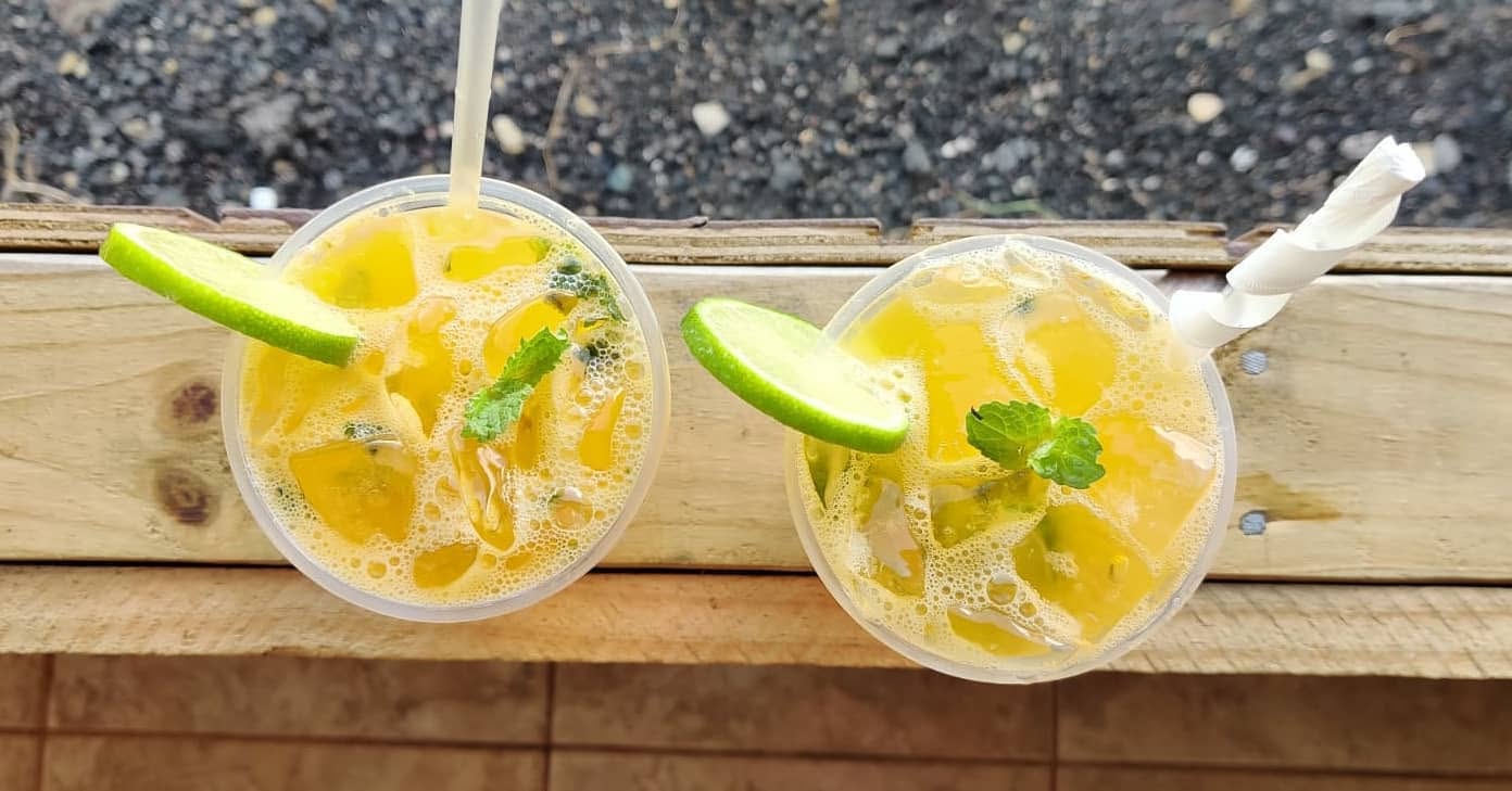 Dos bebidas frías con menta y limón sobre la baranda de madera