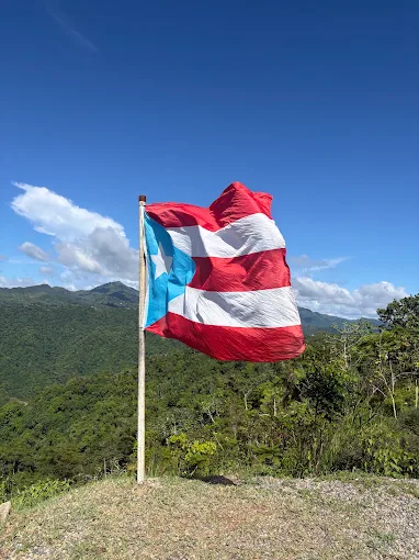Bandera de Puerto Rico ondeando al sol sobre la montaña