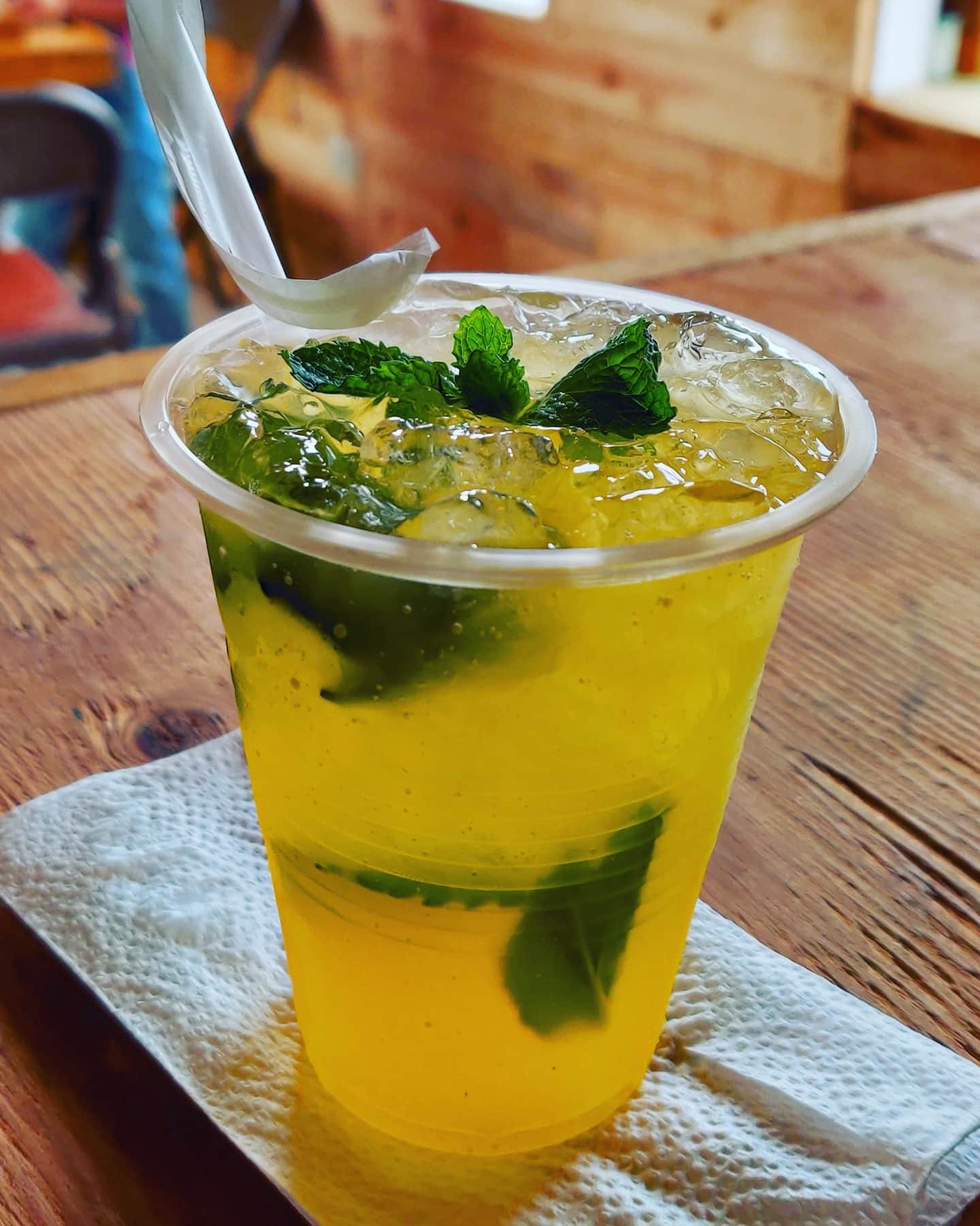 Vaso de bebida fría con hielo y menta sobre una mesa de madera