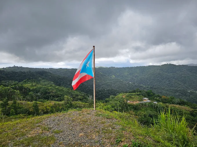 Bandera de Puerto Rico sobre la montaña bajo nubes de aguacero